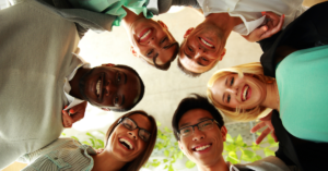People huddling around a camera staring down and smiling